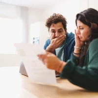 A young married couple is worried looking at the electricity bill or the arrival of very expensive taxes - lifestyle concept on the contemporary family cost of living